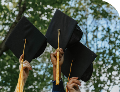 Students hold up graduation caps.