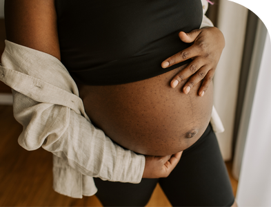 Black pregnant woman holds belly.
